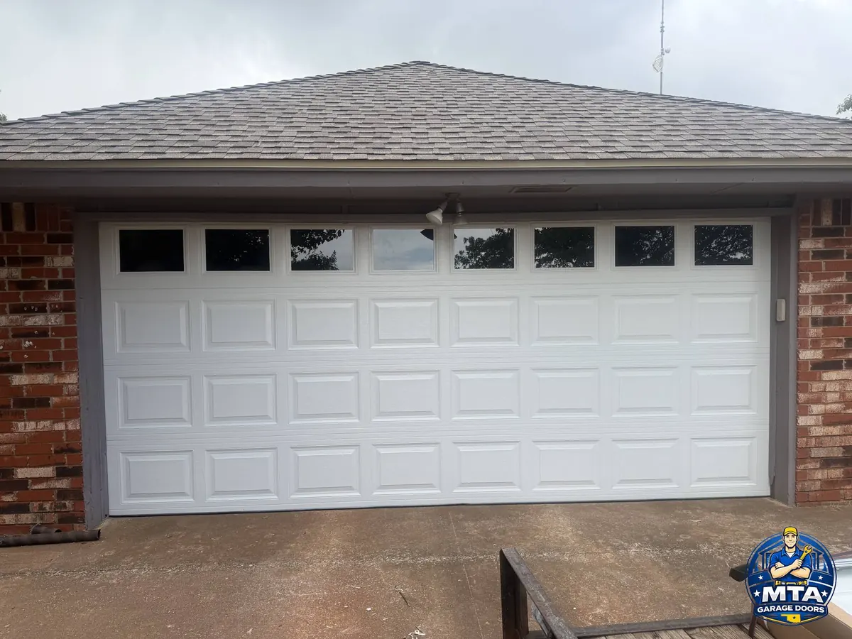 White sectional garage door with windows on a brick home