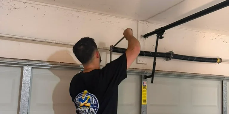 MTA technician working near a residential garage door spring system